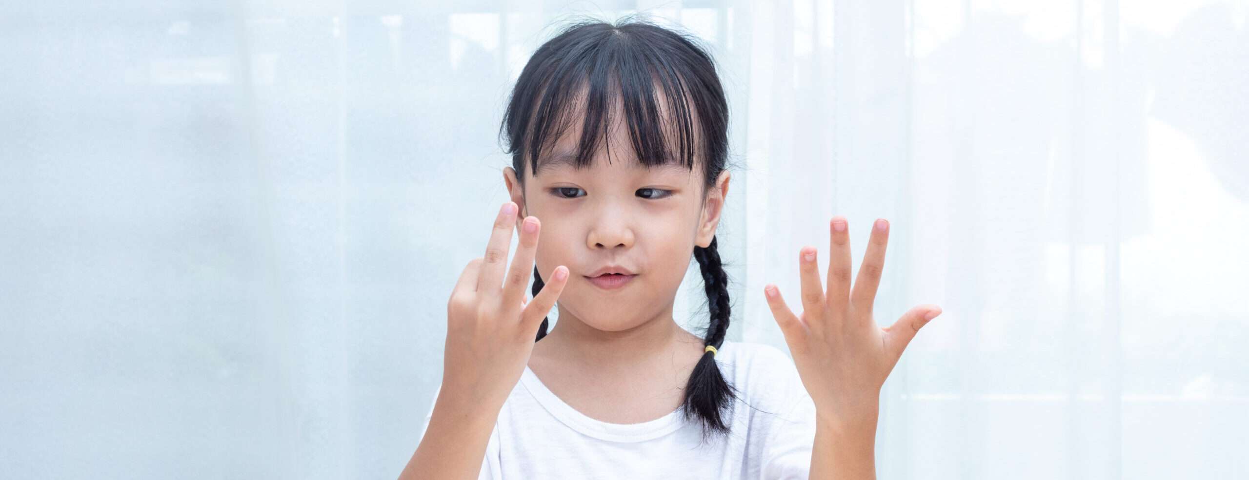 中国の窓の前で小さな女の子が手をかざしている。