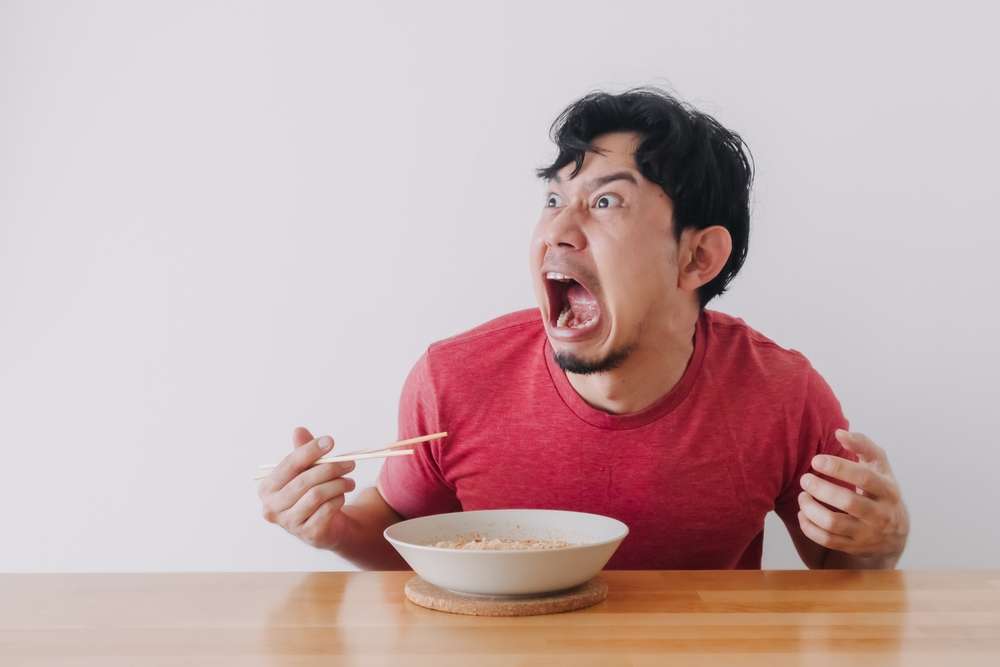 口を開けて麺を食べる男性。