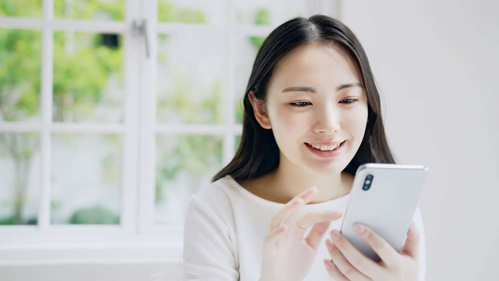 携帯電話を見ている若い中国人女性。 携帯電話を見ている若い中国人女性。