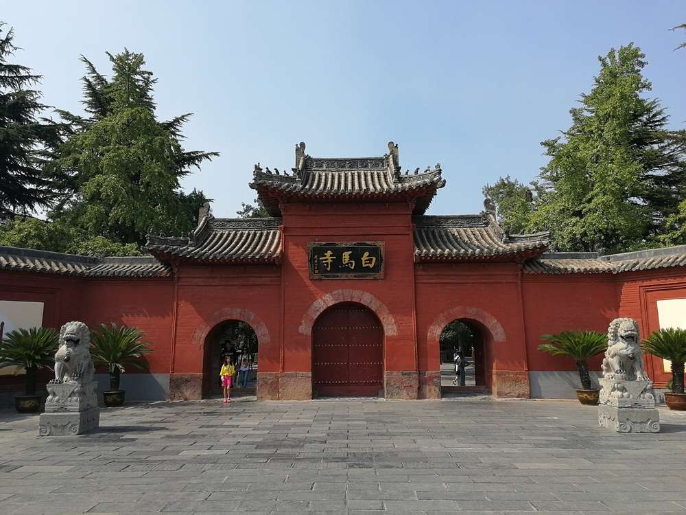 澄んだ青い空の下に狛犬の像がある伝統的な中国の門。