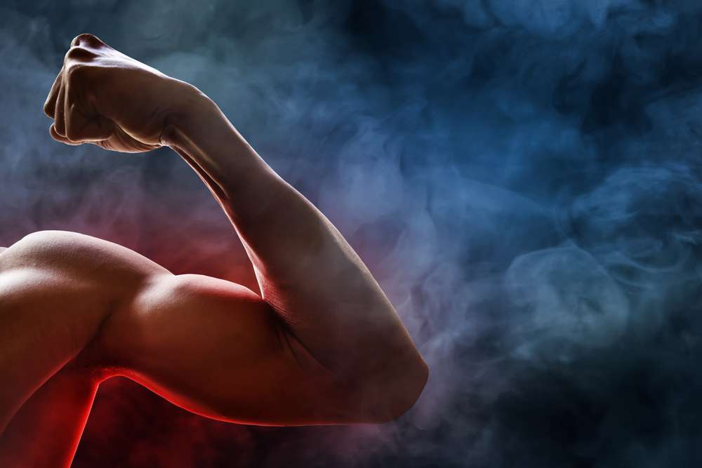 青と赤の煙を背景に曲げられた筋肉質の腕のクローズアップ。伝統的な中国武術を彷彿とさせる力強さと決意が感じられます。