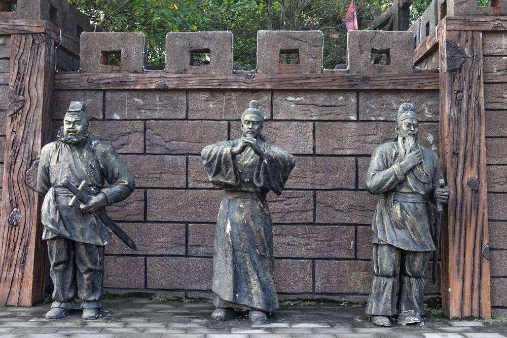 伝統的な中国の衣装を着た古代中国の人物像 3 体が、城壁の狭間溝のある石壁に立っており、リアルなポーズと精巧なディテールが表現されています。 伝統的な中国の衣装を着た古代中国の人物像 3 体が、城壁の狭間溝のある石壁に立っており、リアルなポーズと精巧なディテールが表現されています。