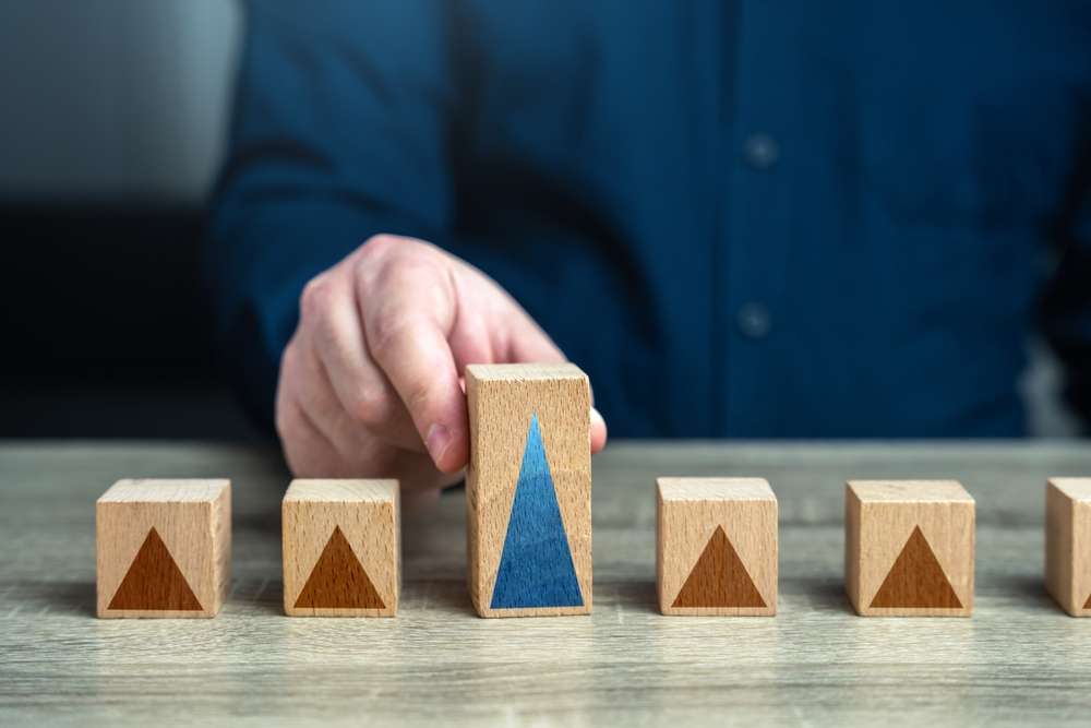 ある人物がテーブルの上に木のブロックを並べている。1 つのブロックには青い三角形があり、他のブロックには茶色の三角形がある。青いシャツを着た人物は、まるで古代中国のパズルを解くかのように、整然と各ピースを配置している。 ある人物がテーブルの上に木のブロックを並べている。1 つのブロックには青い三角形があり、他のブロックには茶色の三角形がある。青いシャツを着た人物は、まるで古代中国のパズルを解くかのように、整然と各ピースを配置している。