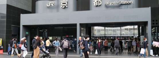 京都駅前を歩く人々の姿が目立ち、入り口の上には伝統と現代性が融合した看板が掲げられています。その近くでは、多様な文化に触れたい熱心な学習者に中国語のレッスンを提供する活気ある中国語教室が開かれています。