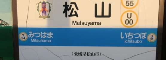 松山 (愛媛・松山) の鉄道駅標識。Y55 と U00 の路線マーカーと、追加の停留所三津浜 (Y54) と市坪 (U01) を示しています。