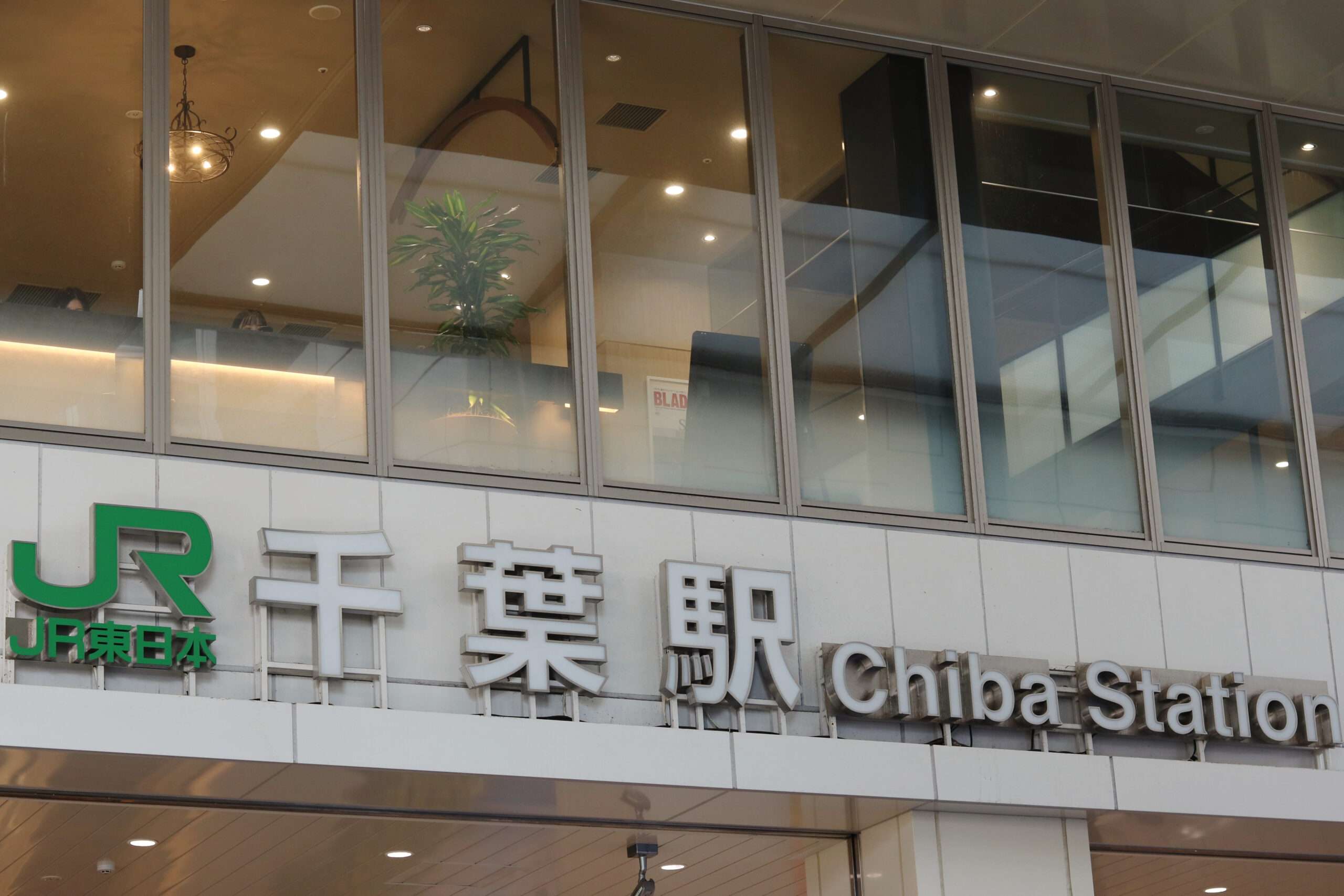 JRのロゴ、大きな窓、ガラスの向こうに見える観葉植物がある千葉駅の標識。