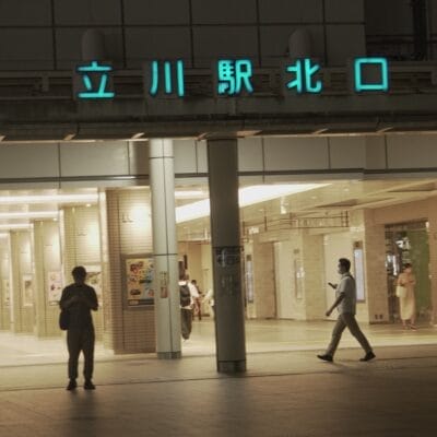 夜、立川駅北口近くの中国語教室の前を通り過ぎる人々。.