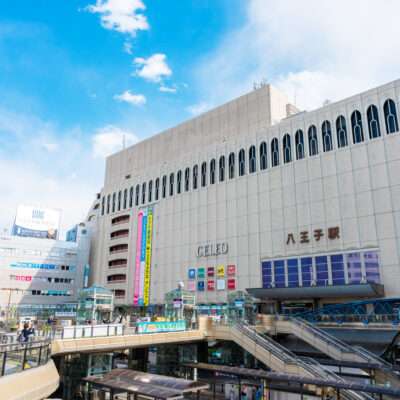 八王子の賑やかな市街地には、大きなデパートや鉄道駅があります。人々は屋外の複数の階を散歩し、明るい標識と澄んだ空が現代の都市景観を引き立てます。近くの中国語教室では、学びたい人向けに語学レッスンを提供しています。