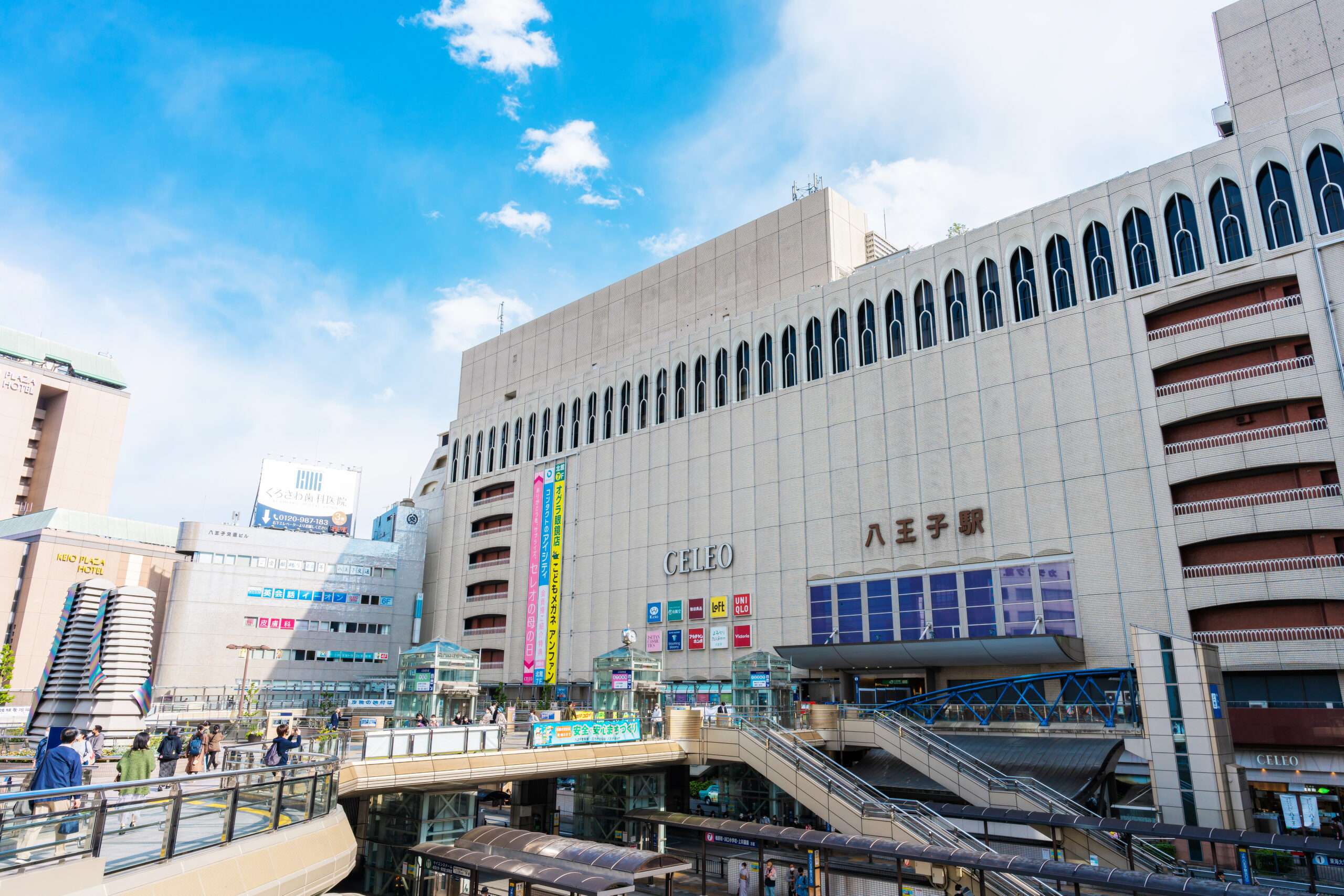 八王子の賑やかな市街地には、大きなデパートや鉄道駅があります。人々は屋外の複数の階を散歩し、明るい標識と澄んだ空が現代の都市景観を引き立てます。近くの中国語教室では、学びたい人向けに語学レッスンを提供しています。