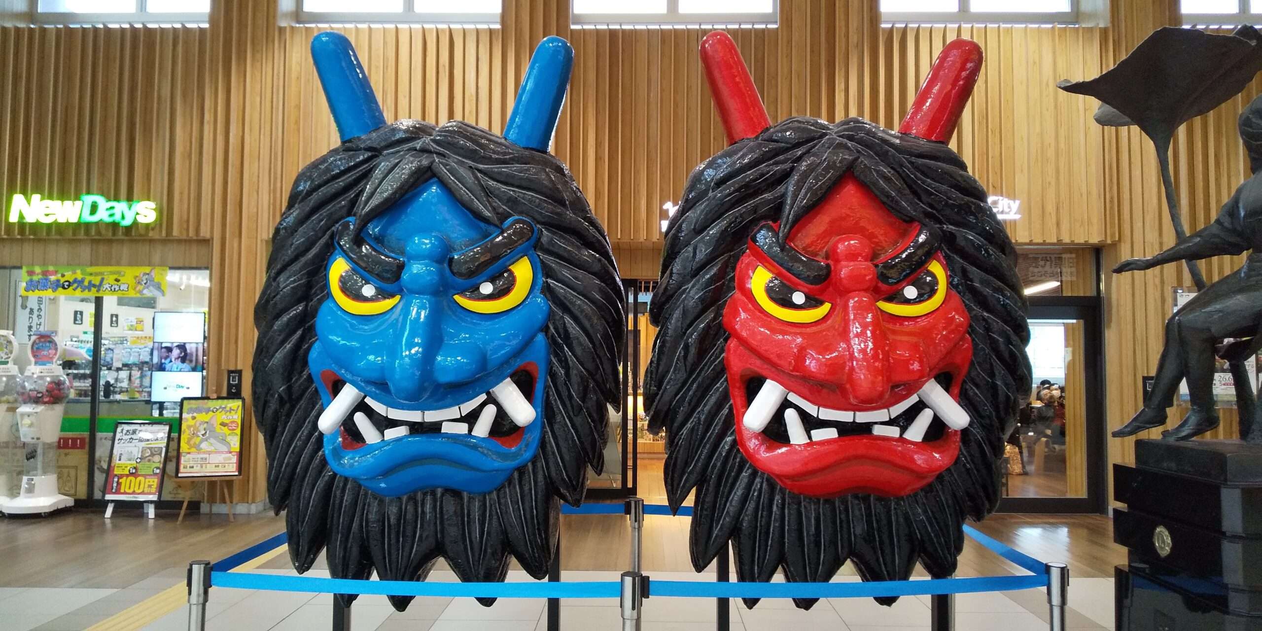 角と牙が付いた大きくて色鮮やかな鬼の面が二つ（印象的な青い秋田模様と燃えるような赤い模様を含む）木の壁を背景に屋内に展示されている。背景の店の看板が本物らしさを醸し出し、まるで古代中国の教室を守っているかのようだ。