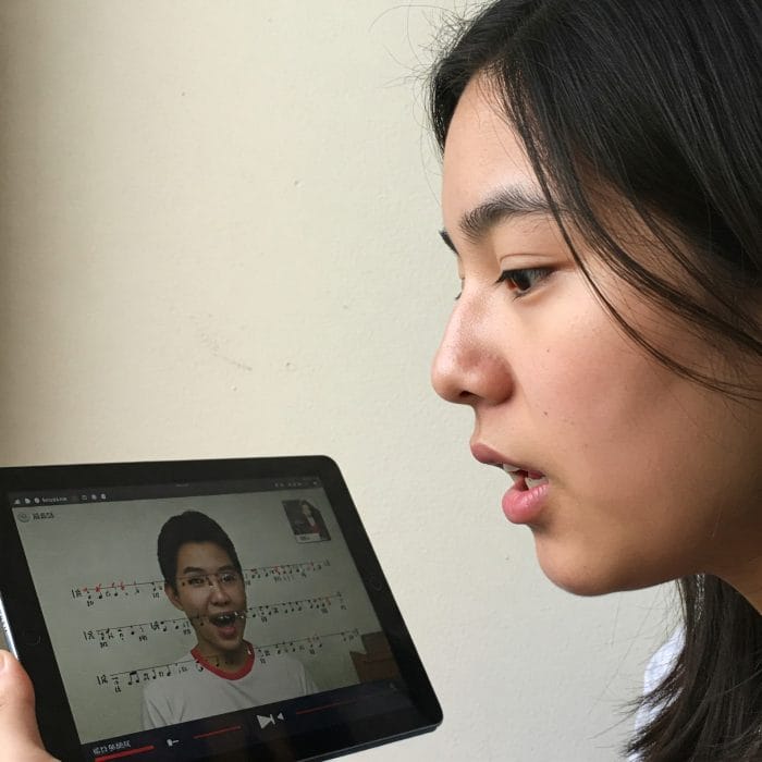 スマートフォンで中国語の歌詞（ピンイン付き）を見ながら発音練習をする人