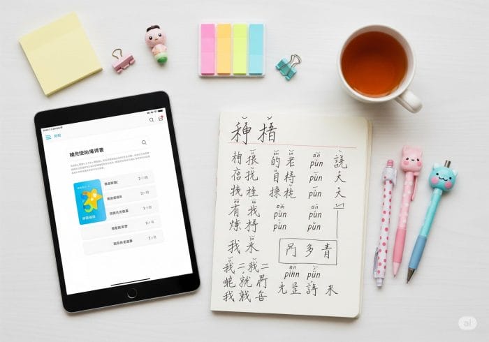 中国語学習アプリが表示されたタブレットとノートが置かれた学習スペースのフラットレイ画像