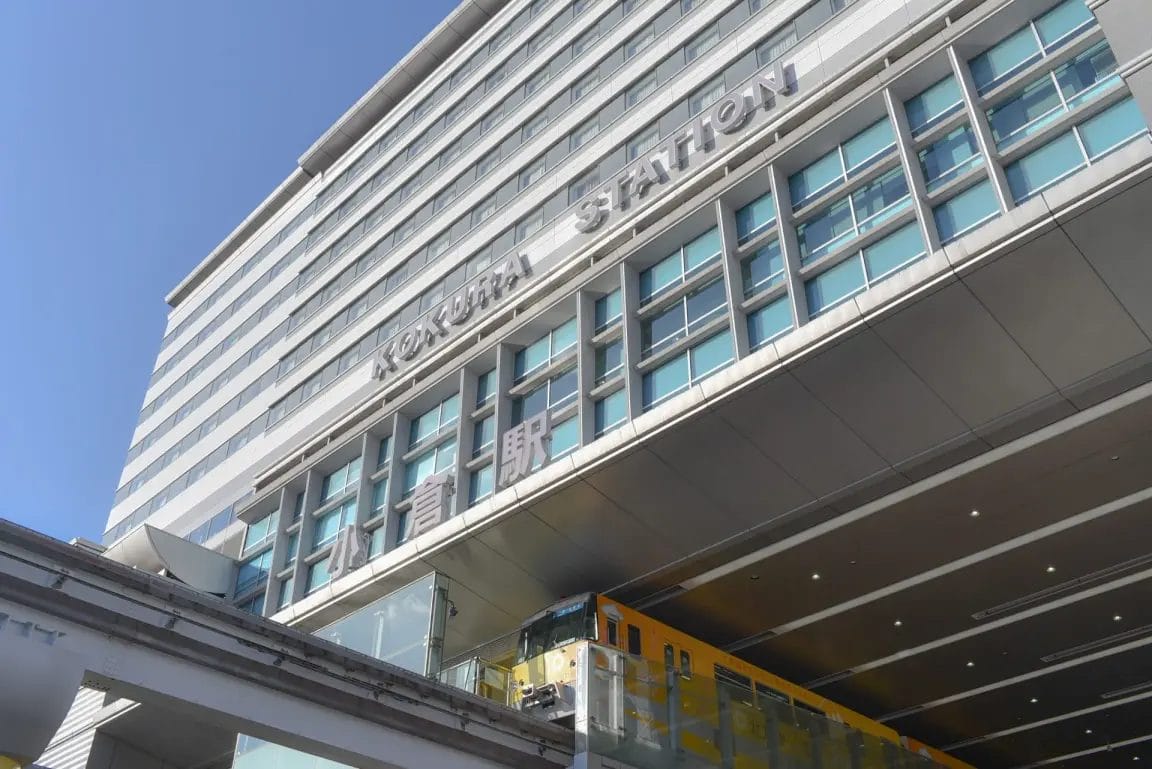 大きな窓と「KOKURA STATION」のサインが入り口の上にある近代的な建物。.