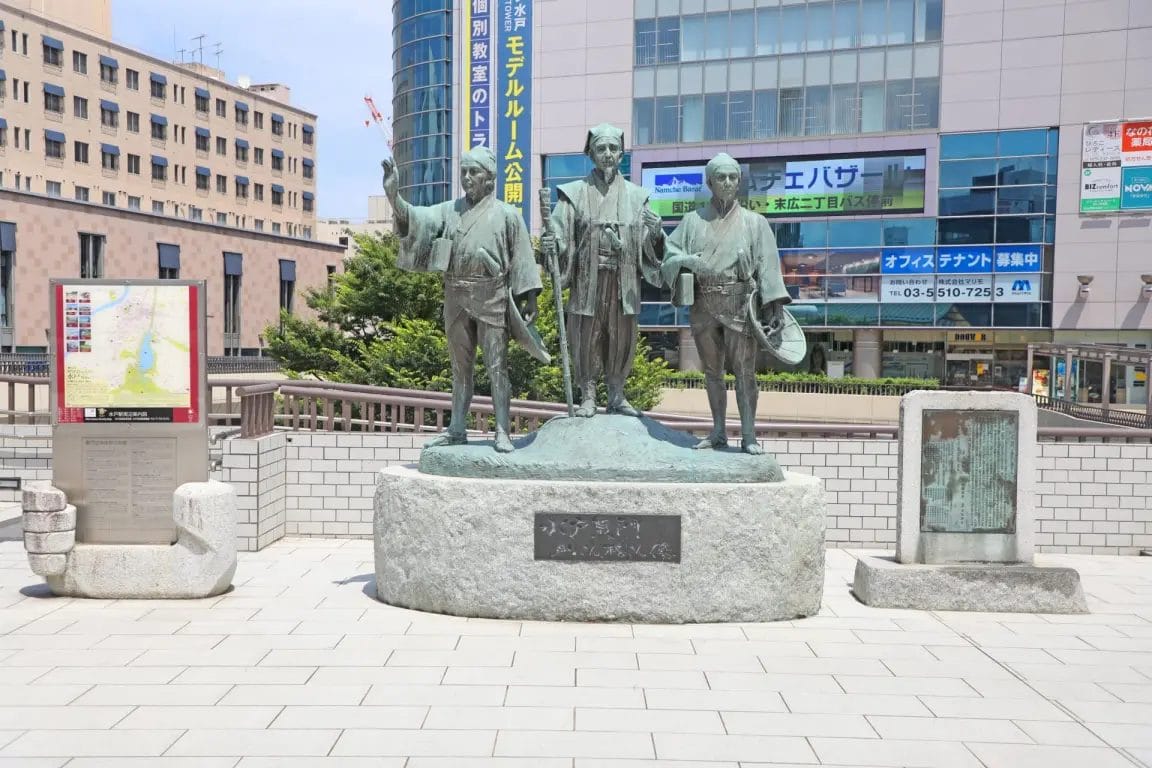 石造りの台座に乗った3人の人物のブロンズ像。.