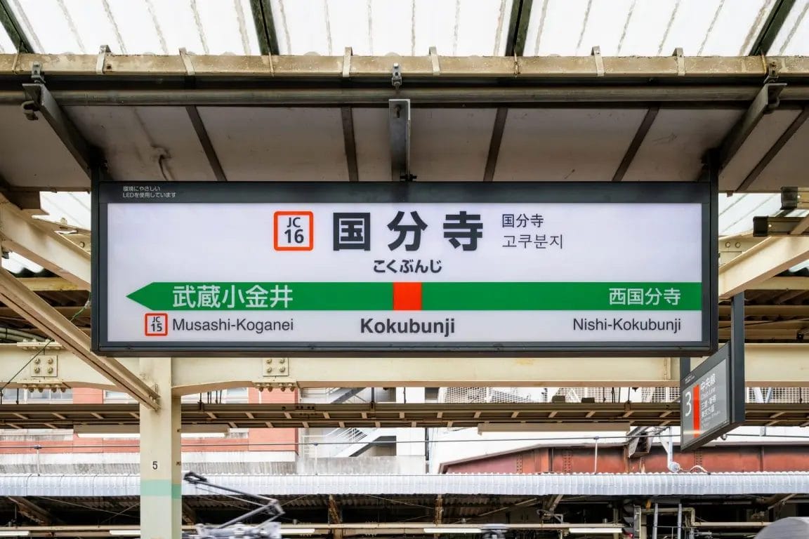 武蔵小金井方面、西国分寺方面を表示する国分寺の駅名標。日本語、英語、ハングルで書かれている。.