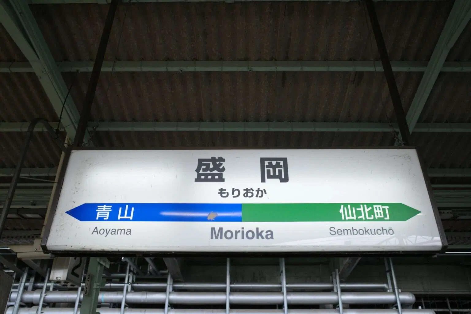 左が青山、右が仙北町への案内が日本語と英語で書かれた盛岡の駅看板。.