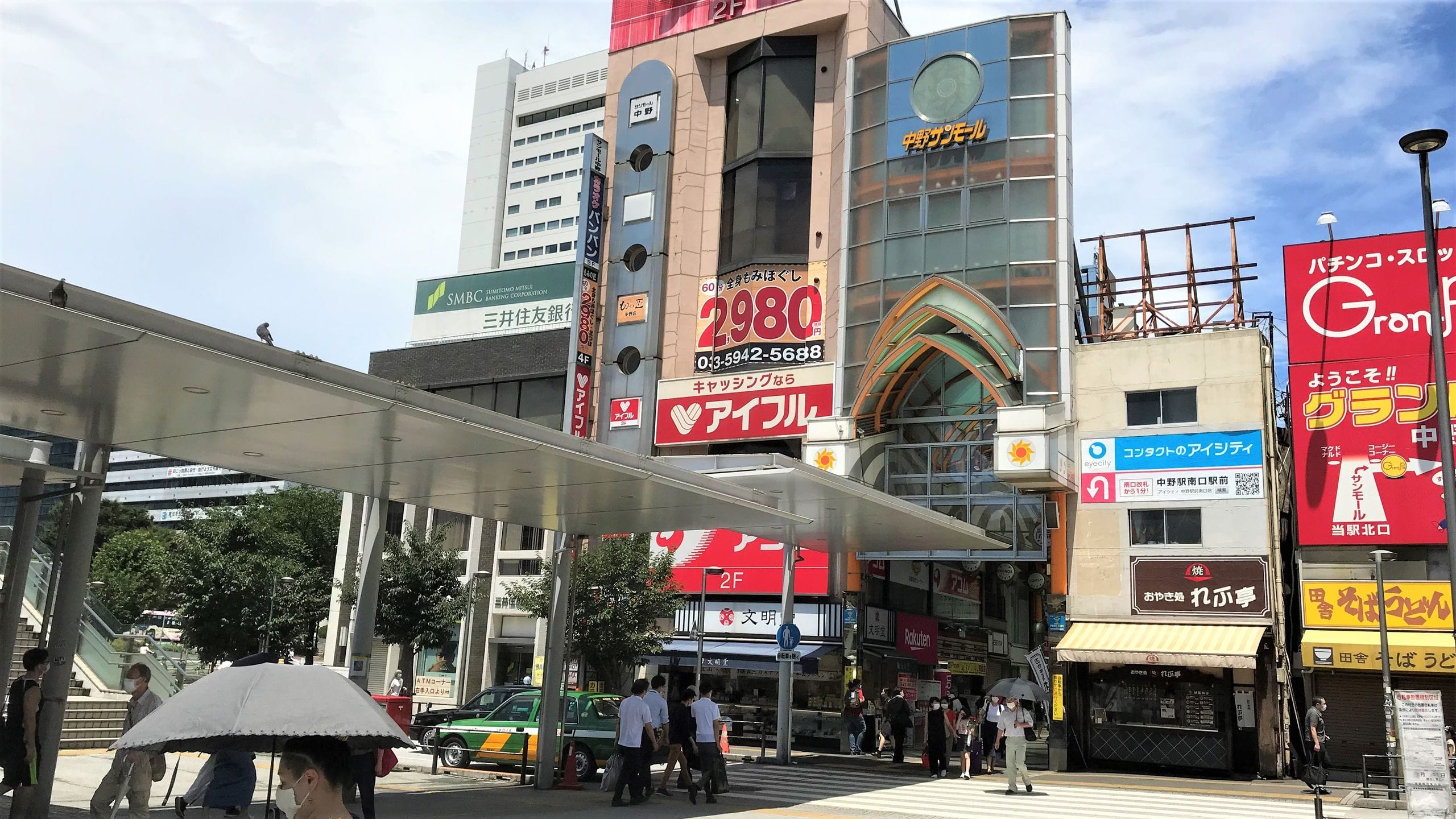 カラフルな日本語の看板や広告が掲げられた高い商業ビルの前の混雑した通りの風景。.