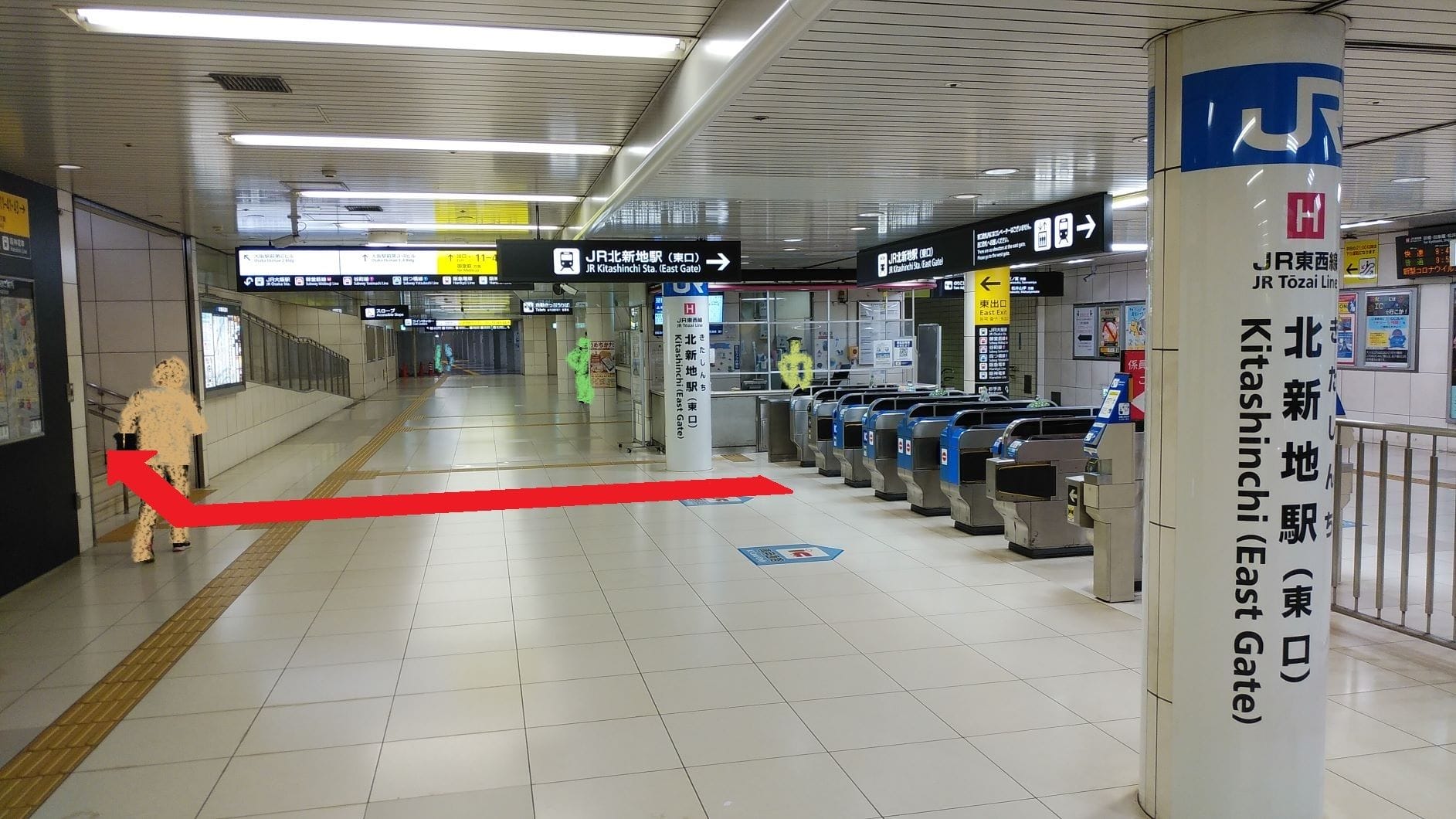 北新地駅東口改札内。右側に改札口があり、通路に沿って大きな赤い矢印が左を向いている。.