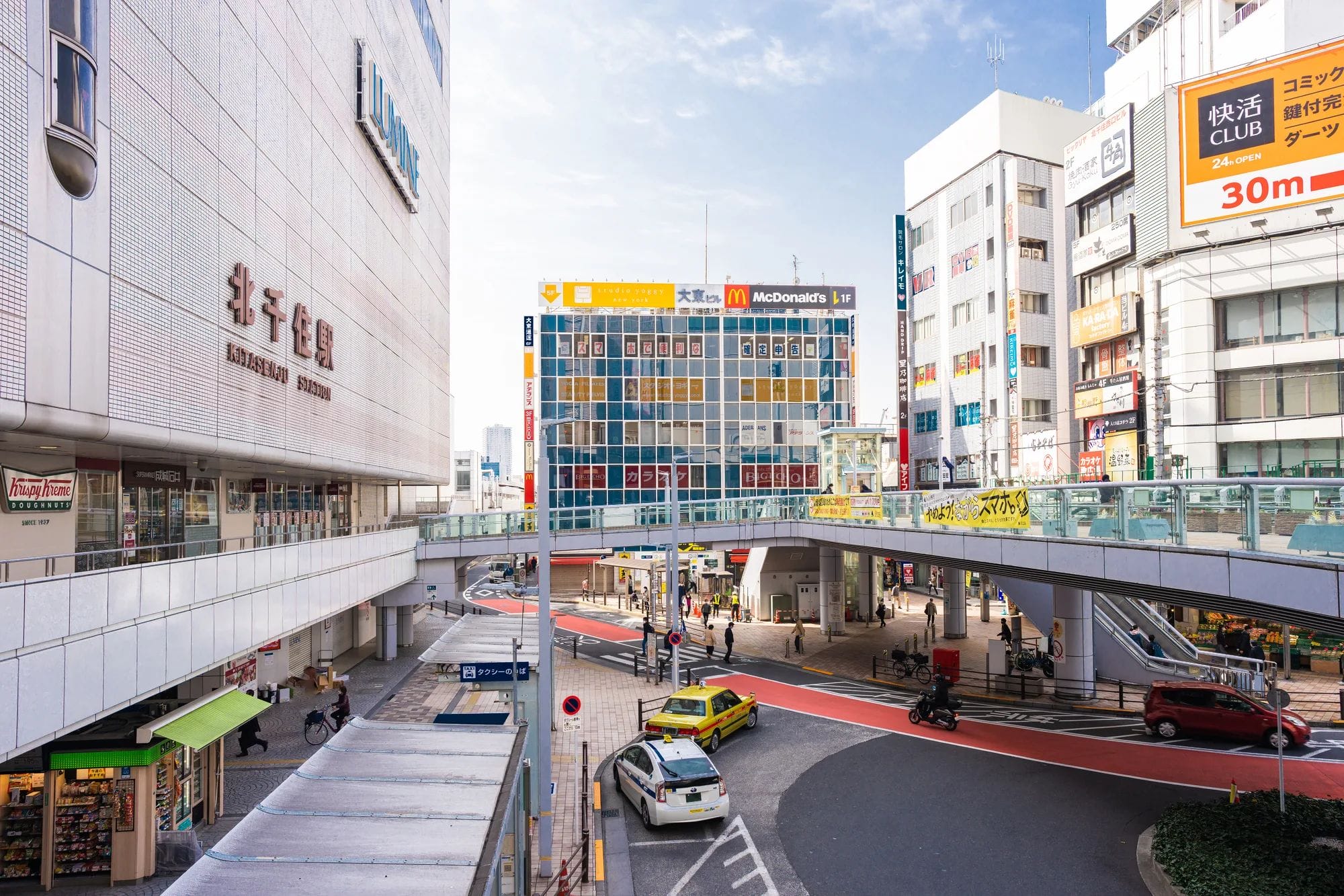 高層ビル、高架歩道、車、自転車、背景に見えるマクドナルドの看板。.